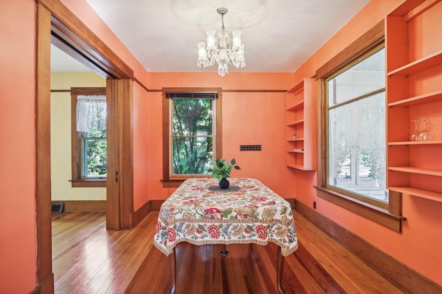 bedroom featuring multiple windows, an inviting chandelier, and hardwood / wood-style floors