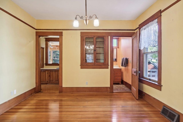 spare room with an inviting chandelier and hardwood / wood-style flooring