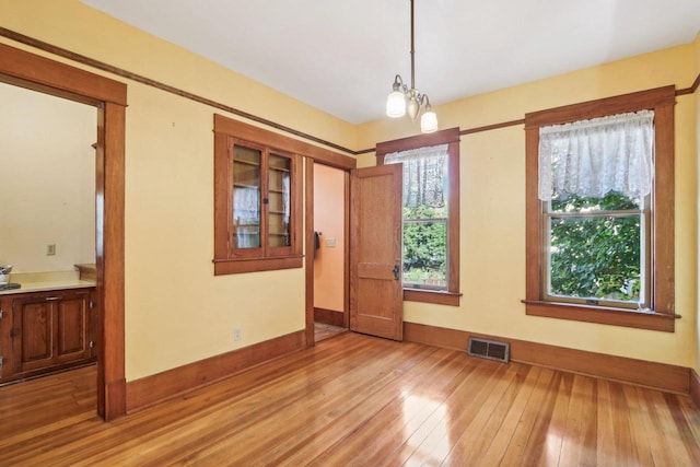 spare room with light wood-type flooring and an inviting chandelier