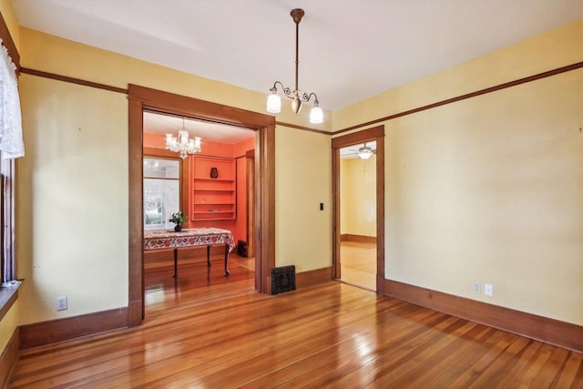 spare room featuring ceiling fan with notable chandelier and hardwood / wood-style floors