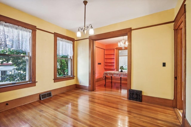 unfurnished room with a notable chandelier and hardwood / wood-style flooring