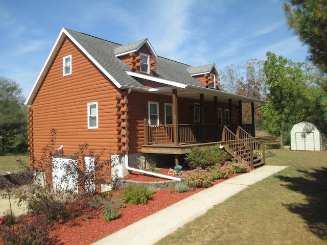 view of front facade featuring a front yard, a porch, and a shed