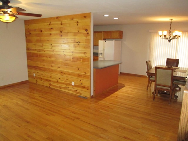 kitchen featuring ceiling fan with notable chandelier, light hardwood / wood-style floors, white fridge with ice dispenser, and decorative light fixtures