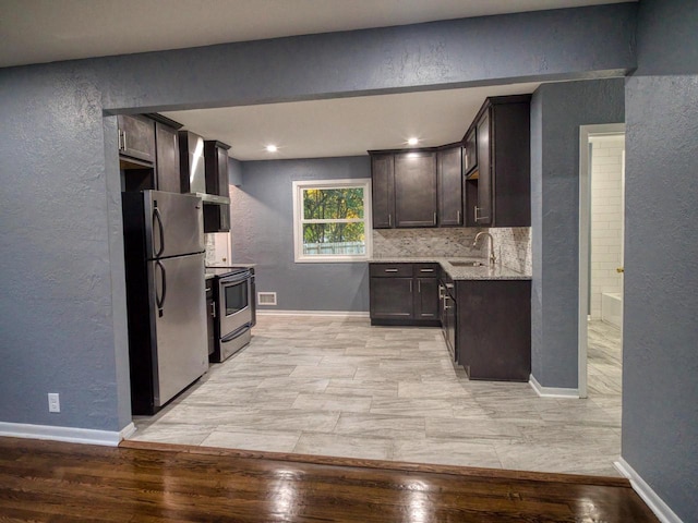 kitchen with appliances with stainless steel finishes, dark brown cabinets, light hardwood / wood-style flooring, and sink