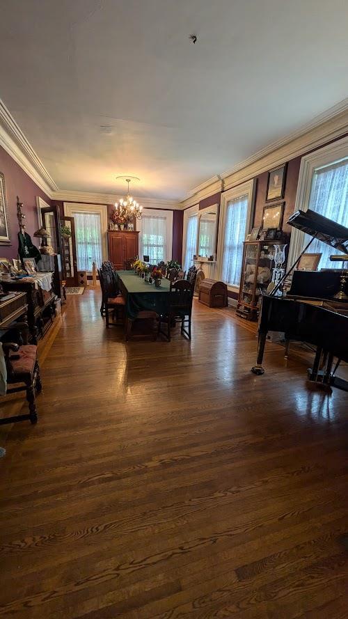 dining area with dark wood-style floors, ornamental molding, and a chandelier