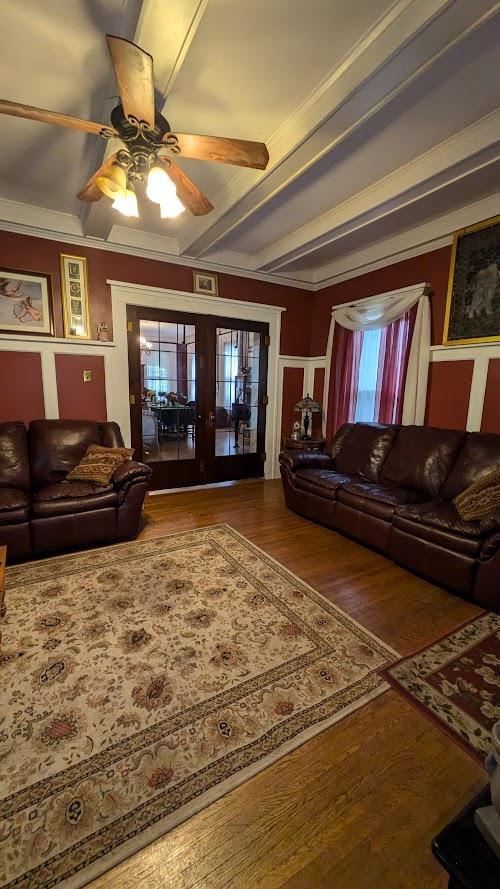 living area featuring a ceiling fan, crown molding, beamed ceiling, and hardwood / wood-style flooring