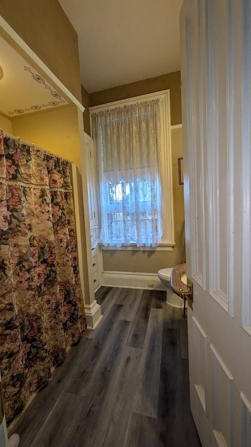 full bathroom featuring toilet and wood finished floors