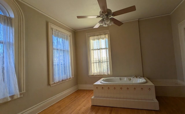 bathroom featuring baseboards, a ceiling fan, ornamental molding, wood finished floors, and a bath