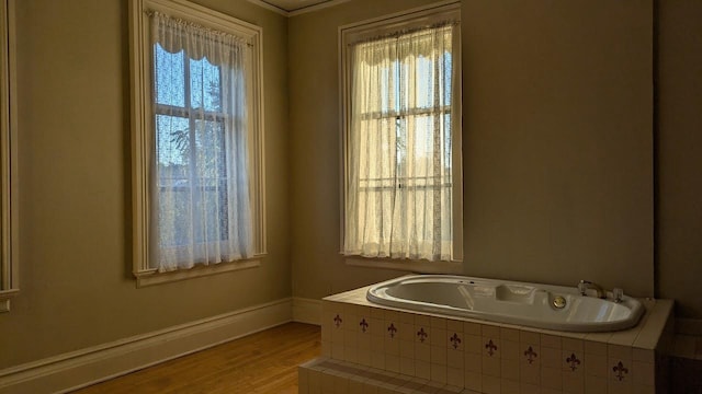 bathroom with a garden tub, baseboards, and wood finished floors