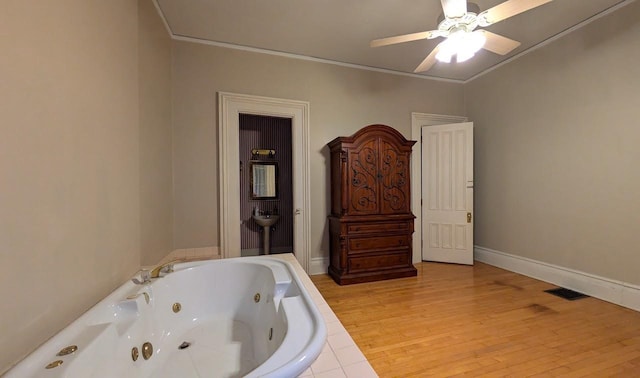 full bath featuring a tub with jets, visible vents, wood finished floors, and ornamental molding