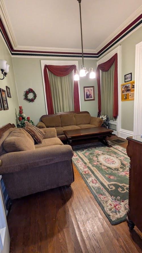 living room featuring crown molding, a notable chandelier, and hardwood / wood-style floors