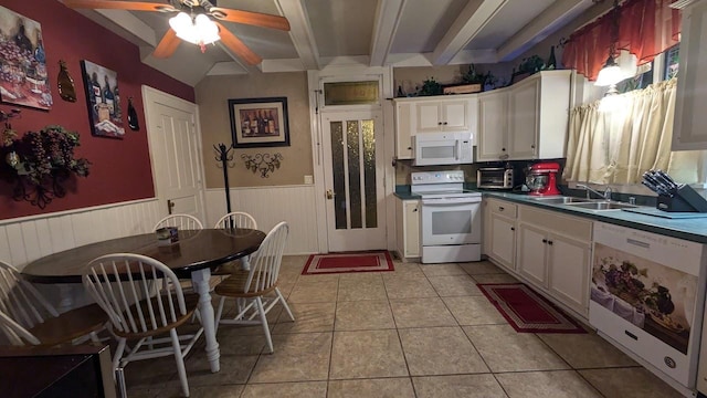 kitchen featuring light tile patterned floors, wainscoting, a sink, white appliances, and beamed ceiling