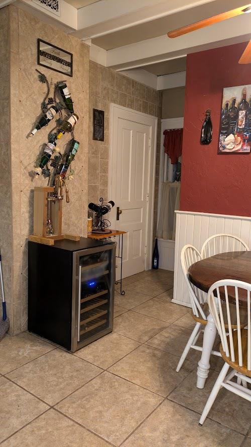 interior space with wine cooler, beam ceiling, and light tile patterned floors