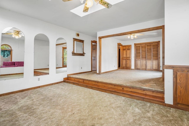 carpeted empty room with ceiling fan and a skylight