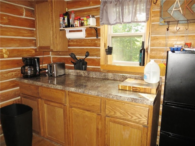 kitchen featuring wood walls and black refrigerator