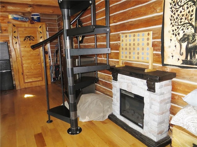 interior space featuring a stone fireplace, log walls, and hardwood / wood-style floors