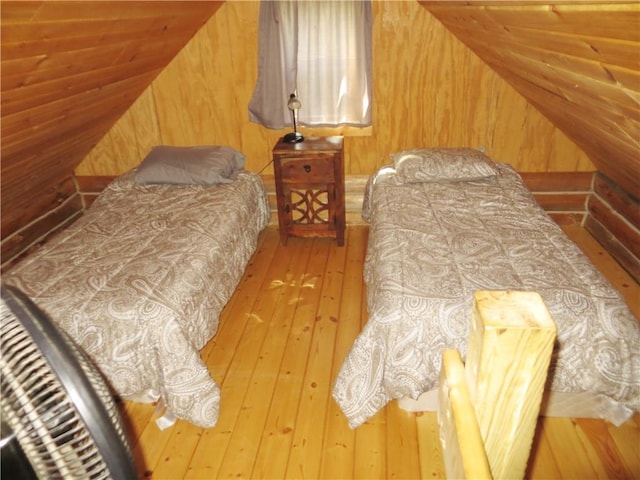 bedroom featuring wooden walls, light hardwood / wood-style flooring, and lofted ceiling