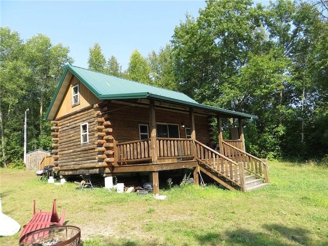 back of house with a fire pit, a yard, and a storage unit