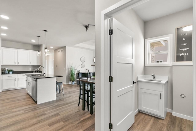 2876 Wild Goose Way, Stoughton, WI 53589 - kitchen with a kitchen bar, white cabinetry, a sink, and light wood-style floors