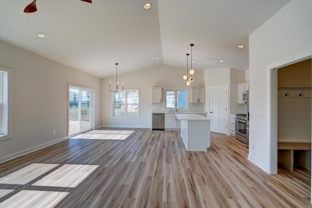 kitchen with white cabinets, a kitchen island, light hardwood / wood-style flooring, appliances with stainless steel finishes, and vaulted ceiling