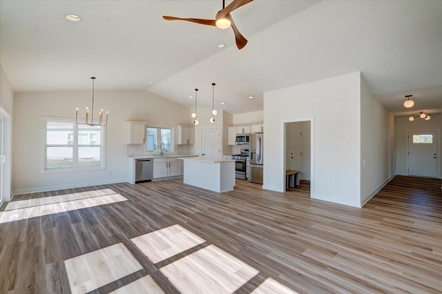 kitchen with white cabinets, appliances with stainless steel finishes, decorative light fixtures, and light hardwood / wood-style flooring