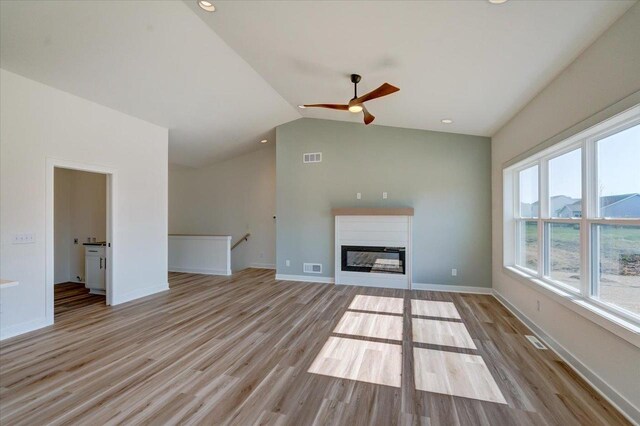 unfurnished living room featuring ceiling fan, light hardwood / wood-style floors, and vaulted ceiling