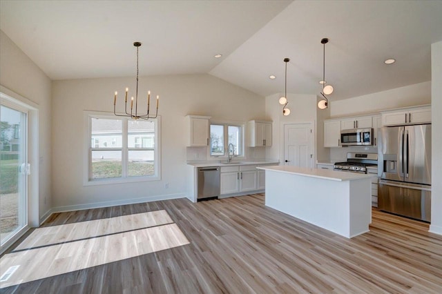 kitchen with stainless steel appliances, a center island, white cabinetry, and a wealth of natural light