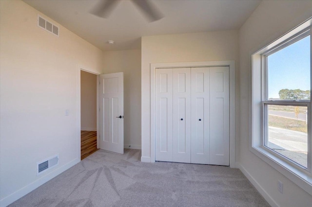 unfurnished bedroom with light carpet, ceiling fan, and a closet