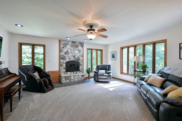 living room with ceiling fan, a stone fireplace, carpet, and a wealth of natural light