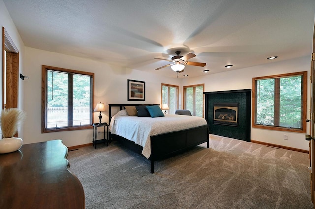 carpeted bedroom with ceiling fan, multiple windows, and a textured ceiling