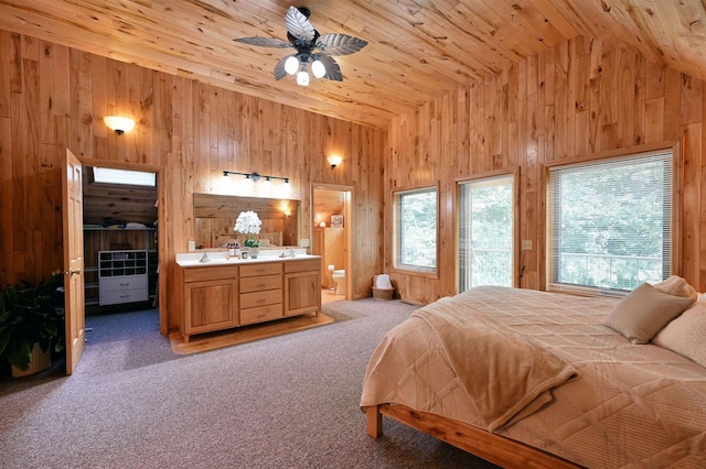 bedroom featuring carpet flooring, wood walls, ensuite bathroom, ceiling fan, and wooden ceiling