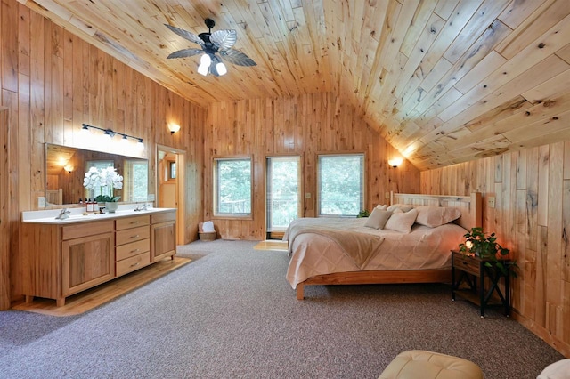 carpeted bedroom with vaulted ceiling, connected bathroom, wooden ceiling, ceiling fan, and wooden walls