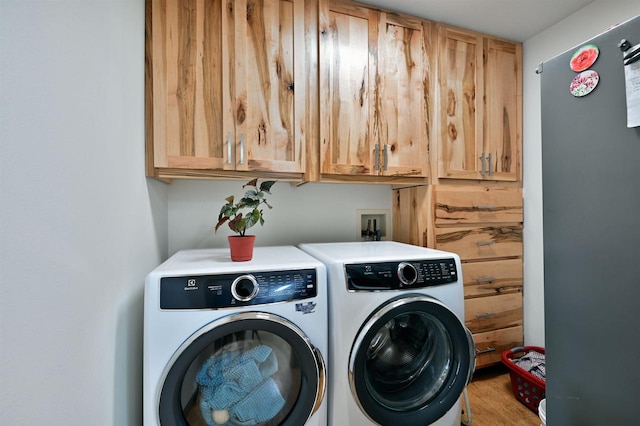 washroom featuring washer and clothes dryer, cabinets, and light hardwood / wood-style flooring