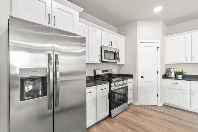 kitchen featuring dark countertops, light wood-style floors, white cabinetry, and stainless steel appliances