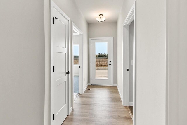 corridor featuring light wood-style flooring and baseboards