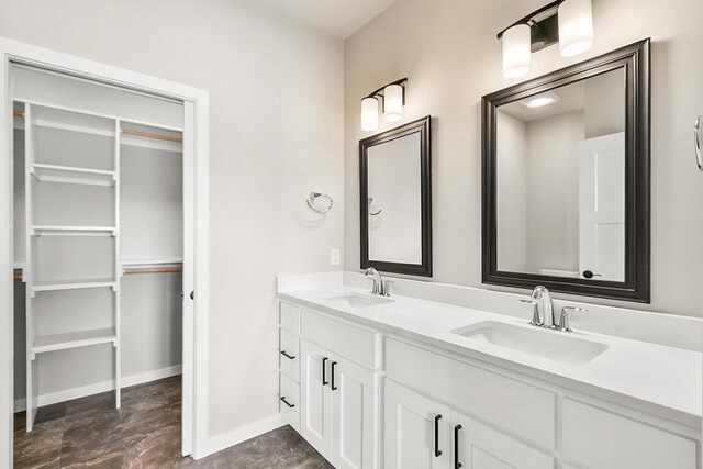 full bathroom with baseboards, double vanity, and a sink