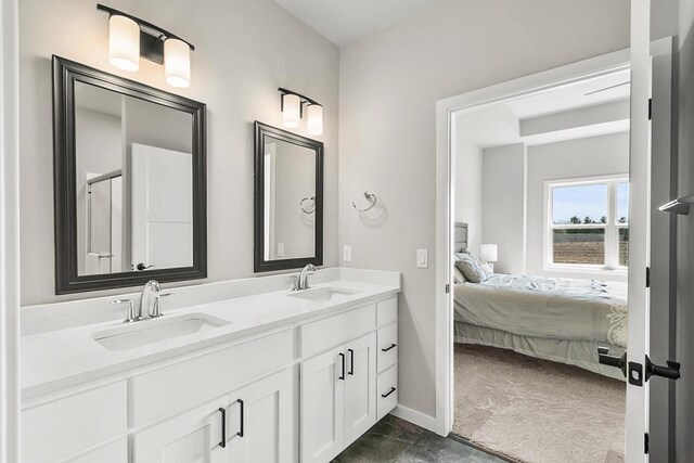 ensuite bathroom with ensuite bathroom, double vanity, baseboards, and a sink