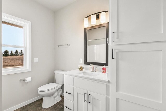 bathroom featuring baseboards, toilet, and vanity