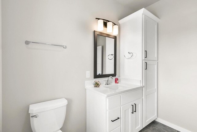 bathroom with baseboards, toilet, and vanity