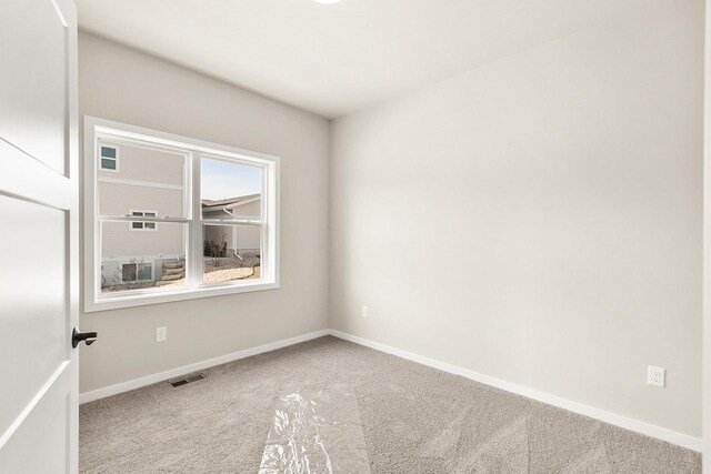 carpeted empty room featuring baseboards and visible vents