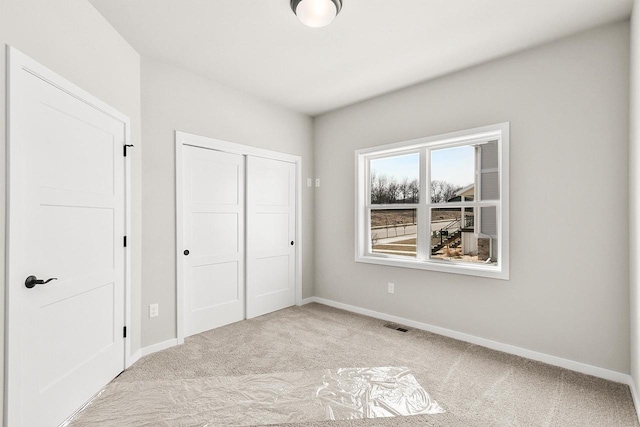 unfurnished bedroom featuring baseboards, visible vents, a closet, and carpet flooring