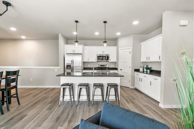 kitchen with a sink, dark countertops, appliances with stainless steel finishes, and a breakfast bar