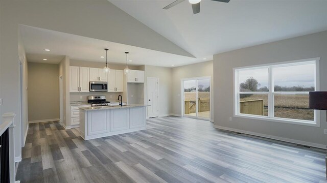 kitchen with appliances with stainless steel finishes, hanging light fixtures, white cabinetry, light wood-type flooring, and ceiling fan