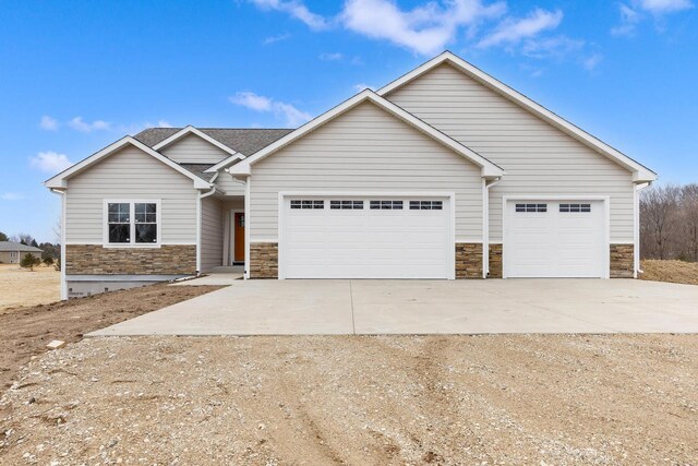 2171 Wallace Lake Rd, West Bend, WI 53090 - view of front facade with driveway, a garage, stone siding, and roof with shingles
