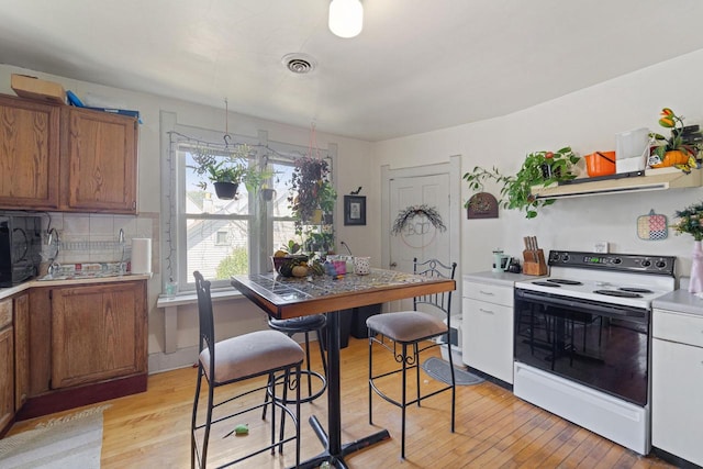 kitchen with light hardwood / wood-style flooring, backsplash, and white electric range