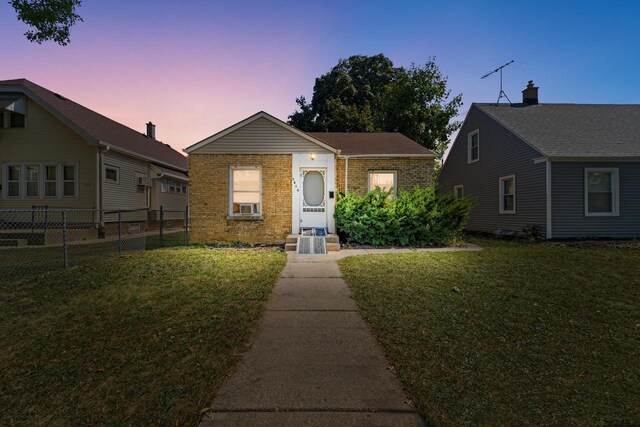 view of front of property featuring a lawn and cooling unit