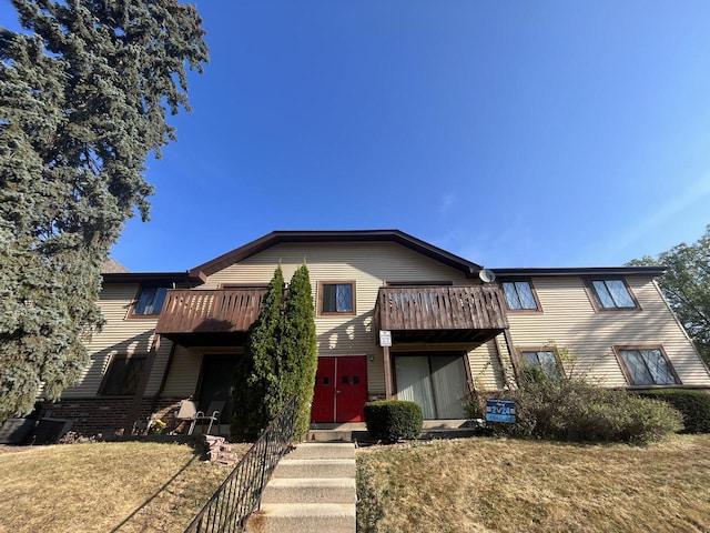 view of front of home featuring a balcony and a front lawn