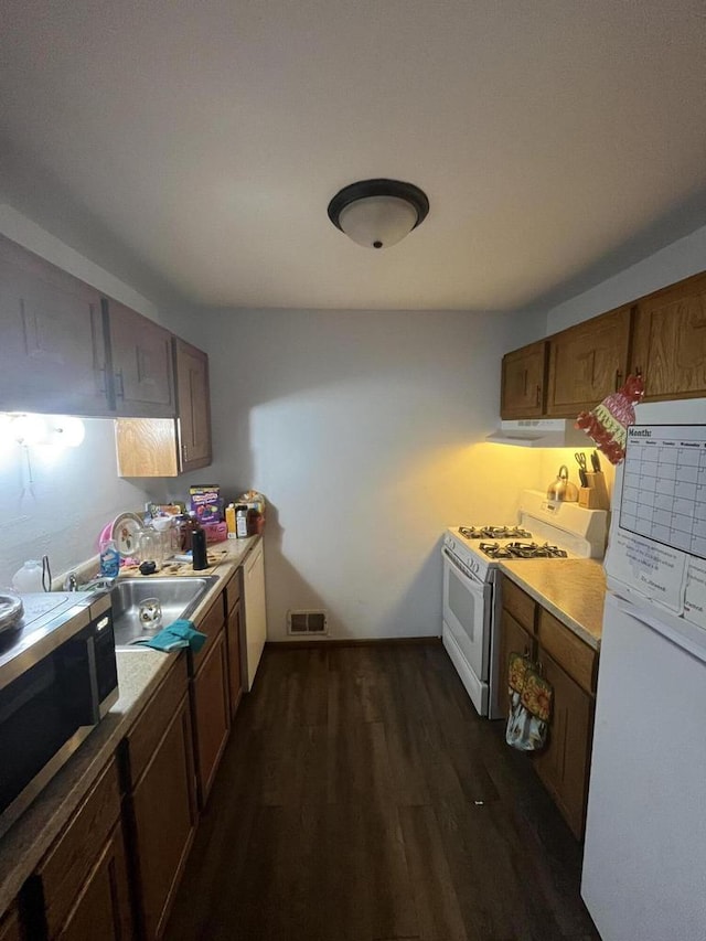 kitchen with white appliances, sink, and dark hardwood / wood-style flooring