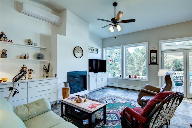 living room with a baseboard heating unit, ceiling fan, hardwood / wood-style flooring, and a wall mounted AC