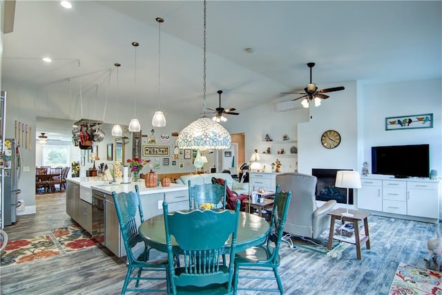 dining area featuring ceiling fan, sink, hardwood / wood-style floors, and vaulted ceiling